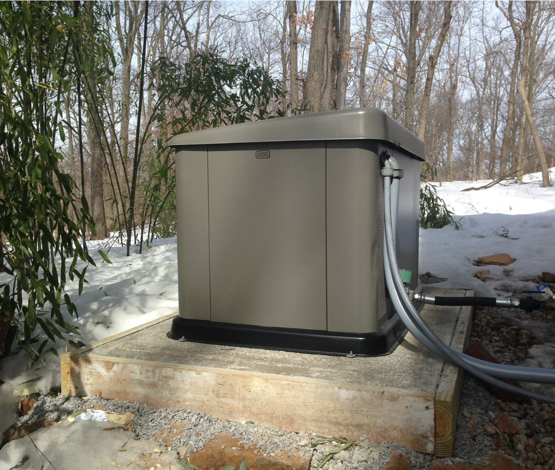 Whole-home standby generator installed beside a house in winter
